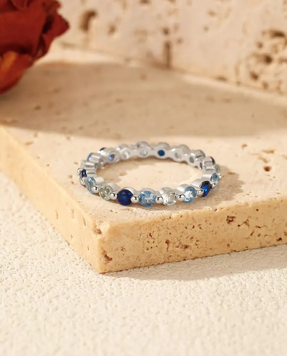 Anello a Giro Completo con Zirconie Blu in Argento 925 - appoggiato su un blocco di travertino