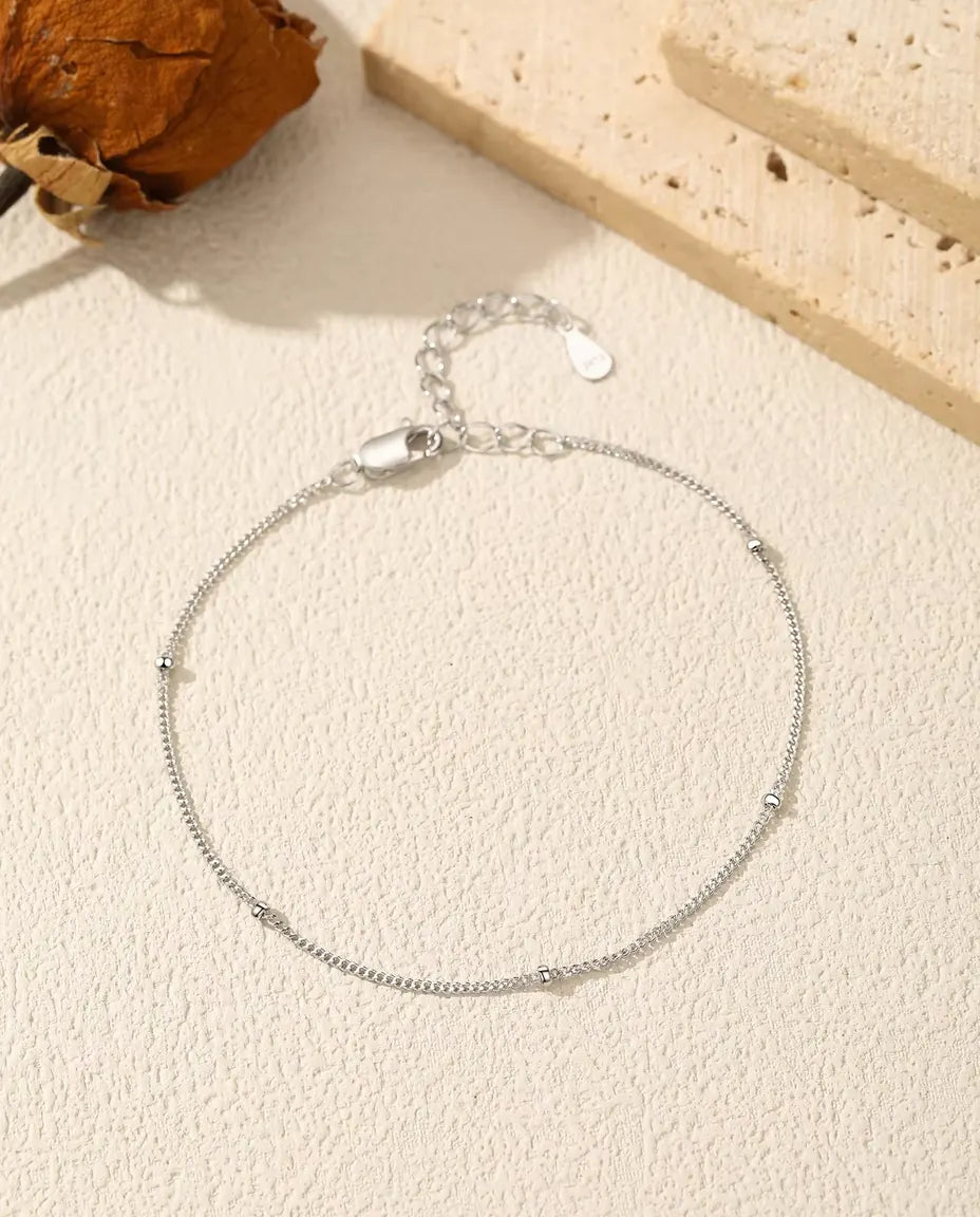 Bracciale Catena Satellite in Argento 925 - disteso su una superficie chiara ruvida, con chiusura e prolunga