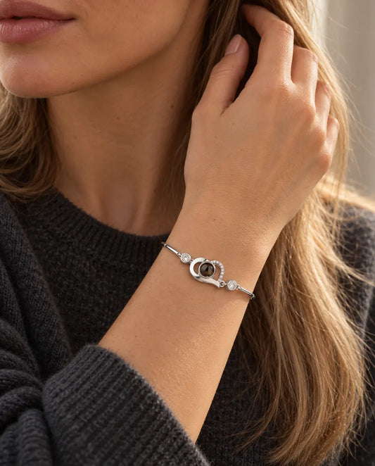 Donna con la mano tra i capelli che indossa il bracciale argentato con cuore aperto e foto dentro