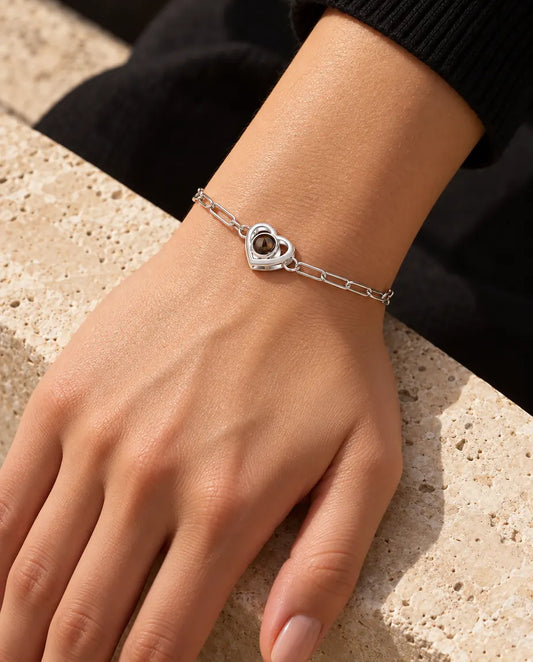 Donna che indossa al polso il bracciale argentato a doppio cuore con foto dentro, alla luce calda del sole