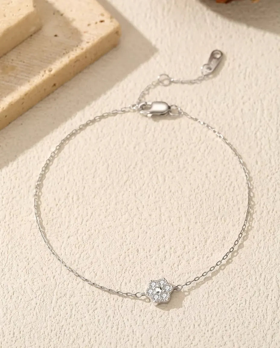 Bracciale Fiore Moissanite in Argento 925 - disteso su una superficie chiara ruvida, con chiusura e prolunga