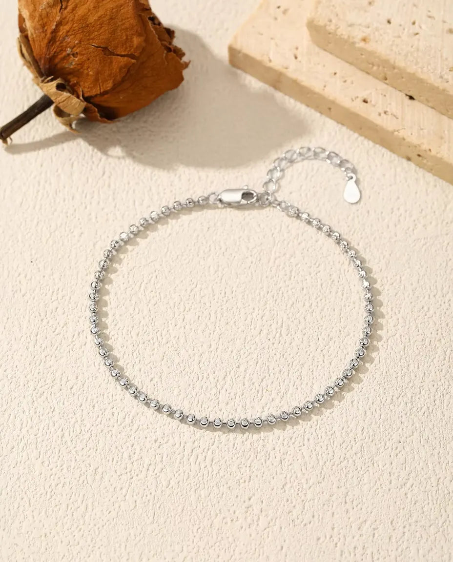 Bracciale con Perline Sfaccettate in Argento 925 - disteso su una superficie chiara ruvida, con chiusura e prolunga