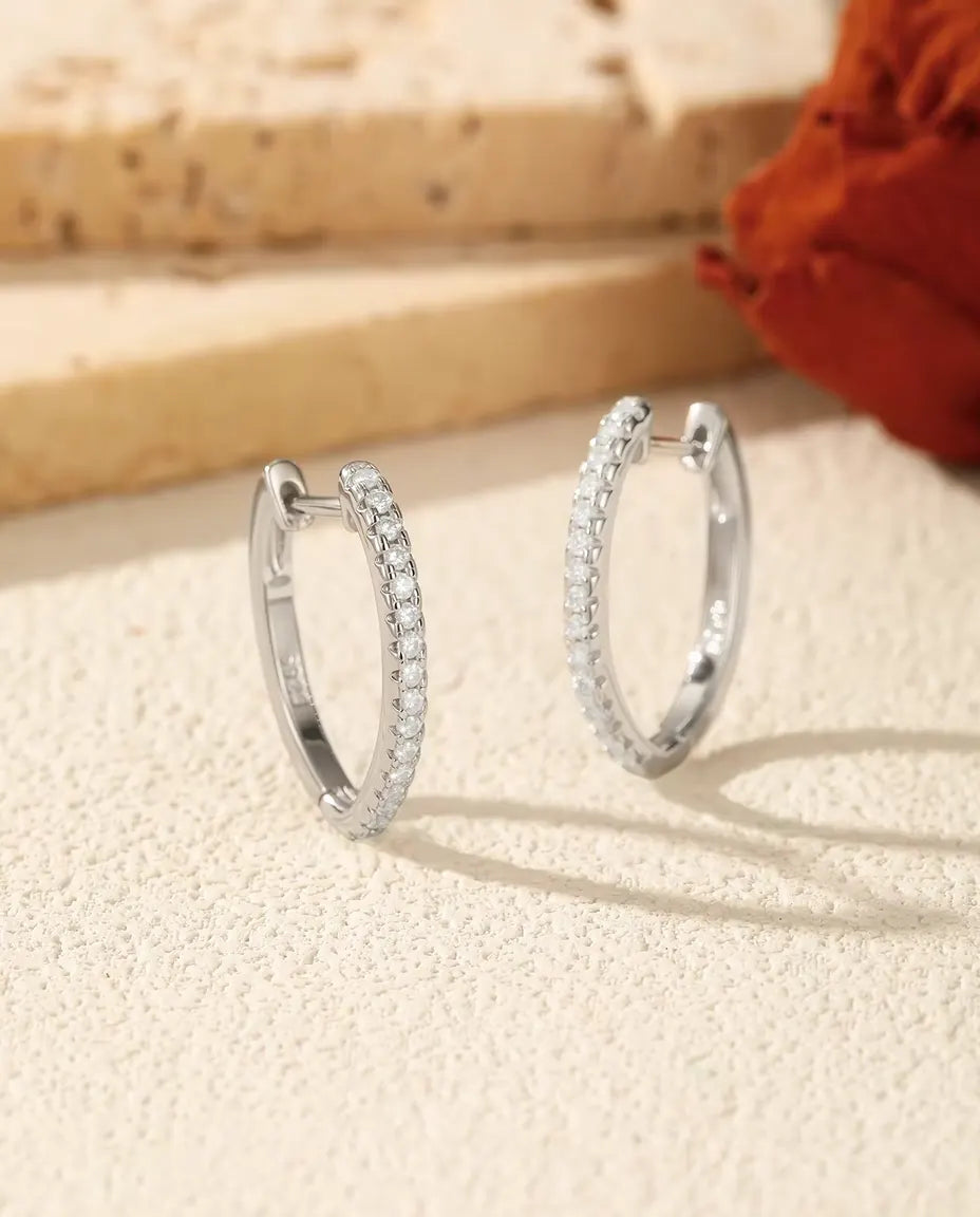 Orecchini a Cerchio con Moissanite a U in Argento 925 - la coppia affiancata su una superficie chiara ruvida