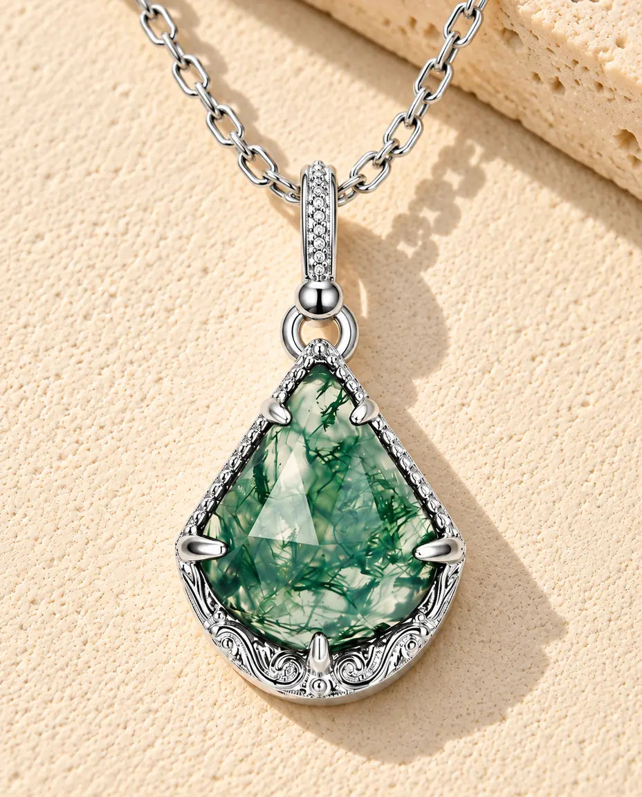 Collana Agata Muschiata Aquilone in Argento 925 - appoggiata su una superficie chiara ruvida accanto a un blocco di travertino