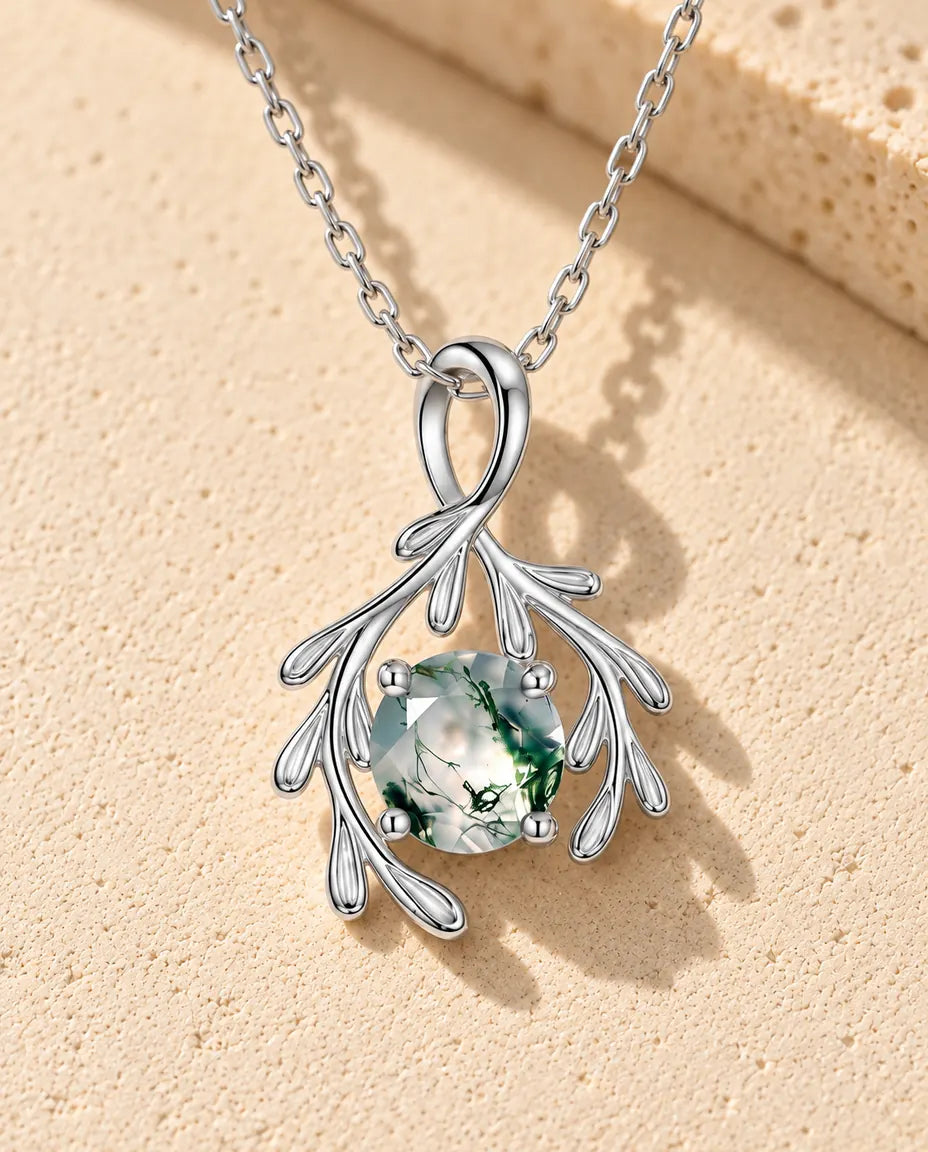 Collana Agata Muschiata Rami in Argento 925 - appoggiata su una superficie chiara ruvida accanto a un blocco di travertino