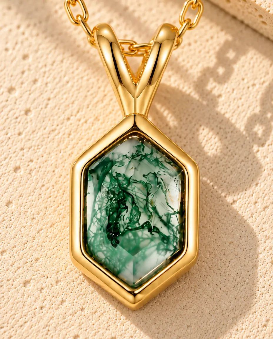 Collana Agata Muschiata Esagonale in Argento 925 Placcato Oro - appoggiata su una superficie chiara ruvida accanto a un blocco di travertino