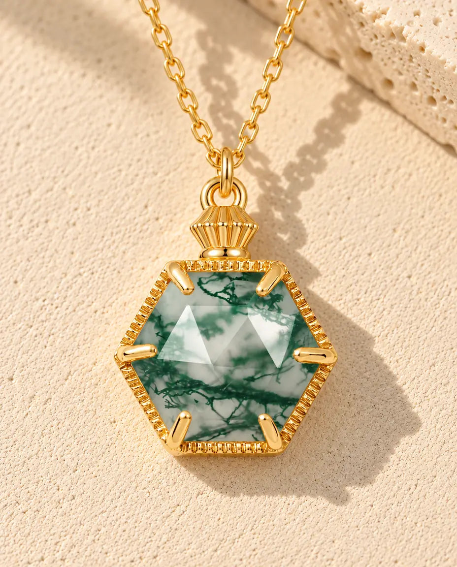 Collana Agata Muschiata Esagonale in Argento 925 Placcato Oro - appoggiata su una superficie chiara ruvida accanto a un blocco di travertino