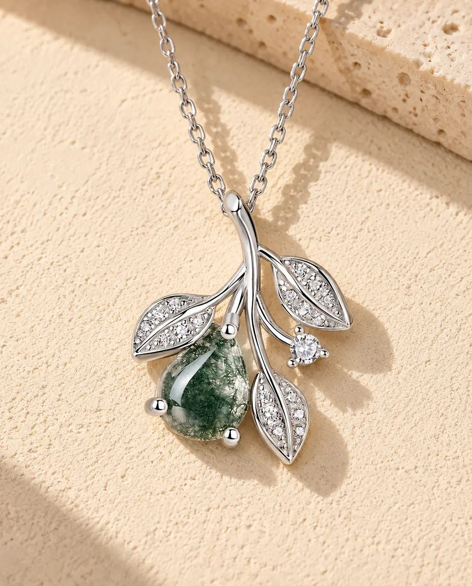 Collana Agata Muschiata con Foglie in Argento 925 - appoggiata su una superficie chiara ruvida accanto a un blocco di travertino