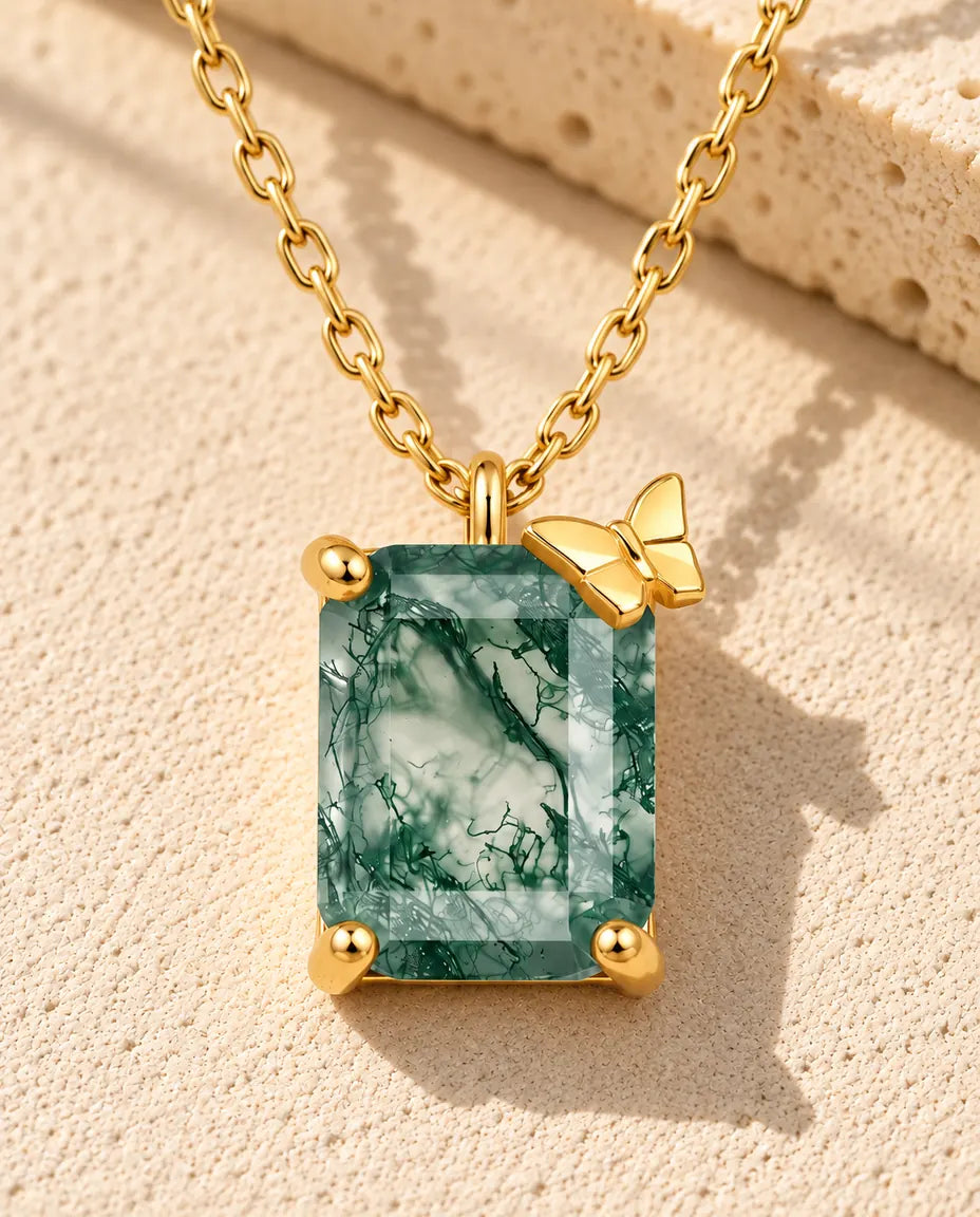 Collana Agata Muschiata in Argento 925 Placcato Oro - appoggiata su una superficie chiara ruvida accanto a un blocco di travertino