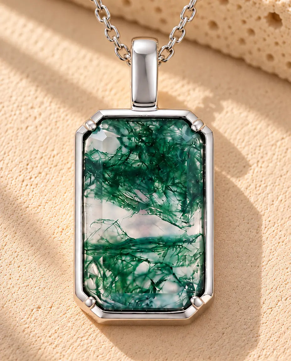 Collana Agata Muschiata Ciondolo Rettangolare in Argento 925 - appoggiata su una superficie chiara ruvida accanto a un blocco di travertino
