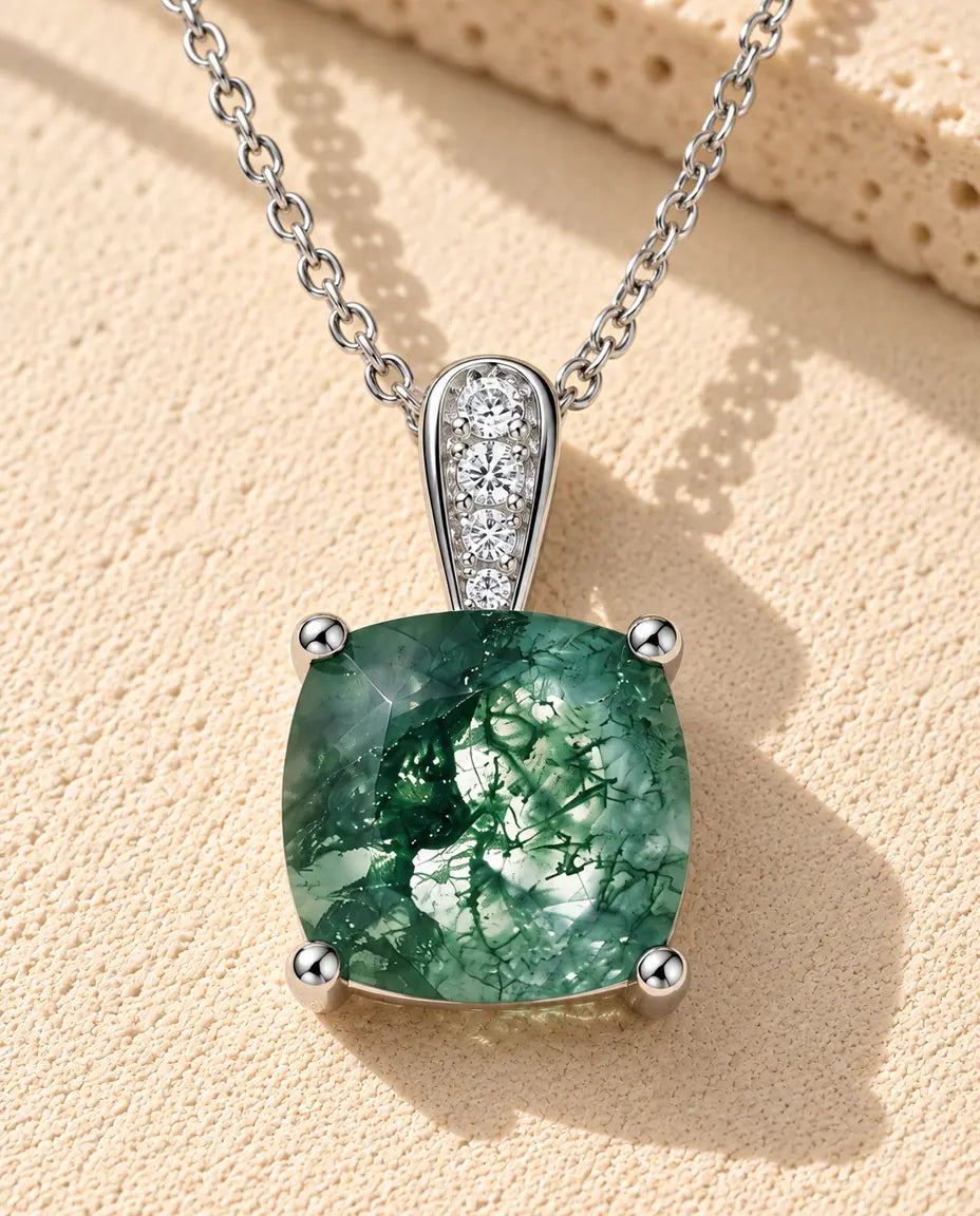 Collana Solitario Agata Muschiata in Argento 925 - appoggiata su una superficie chiara ruvida accanto a un blocco di travertino