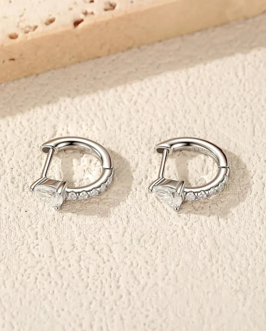 Orecchini Mini Cerchi con Moissanite a Goccia in Argento 925 - la coppia su una superficie chiara ruvida