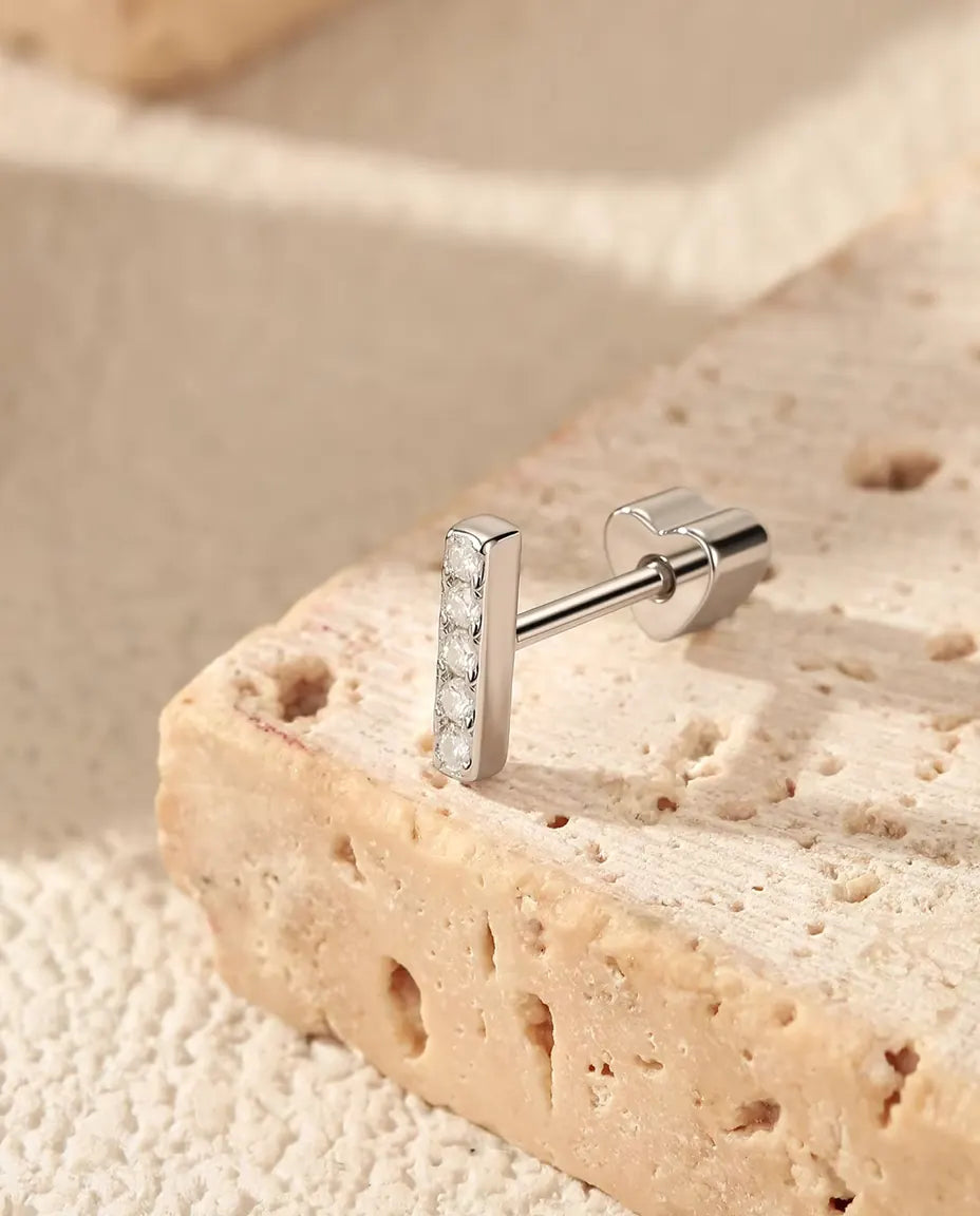 Orecchini a Barretta con Cinque Moissanite in Argento 925 - sul bordo di una lastra di travertino