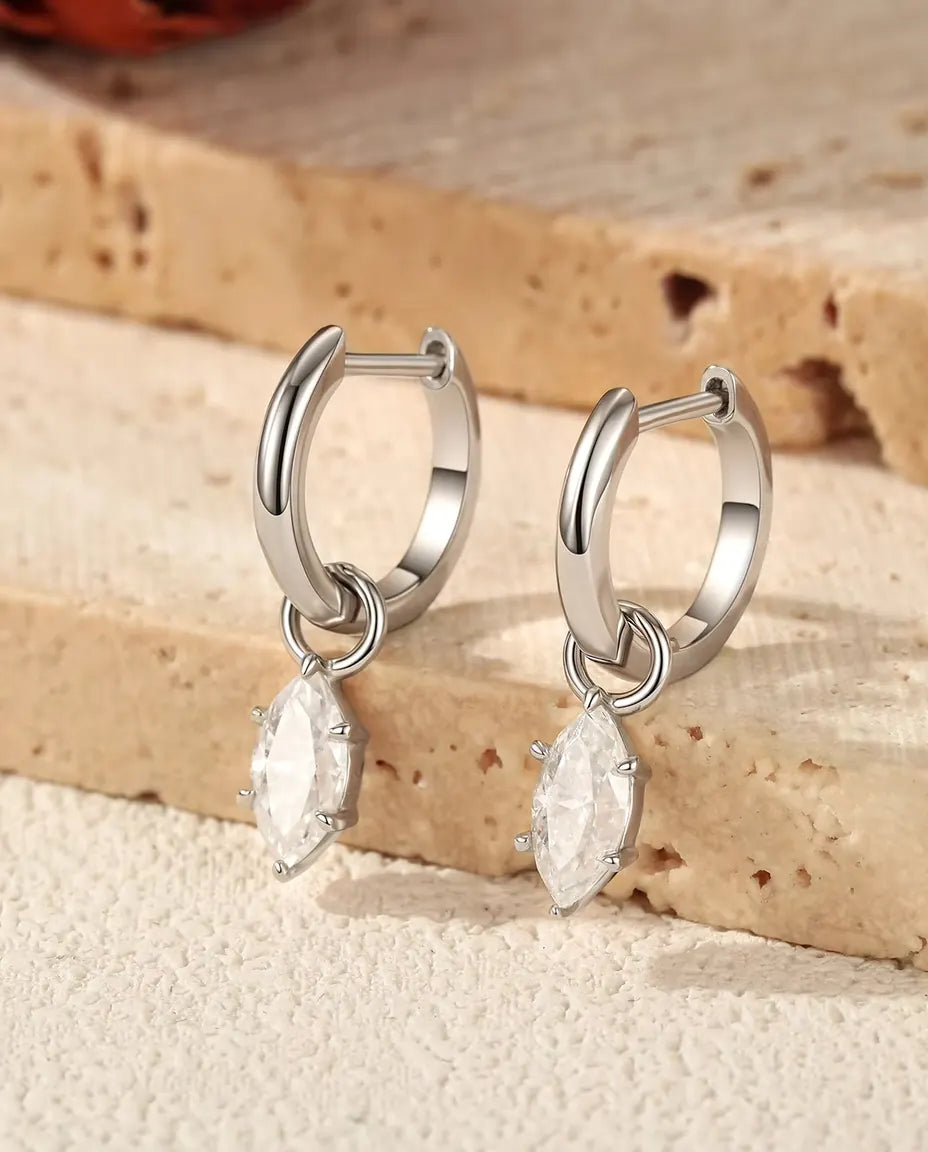 Orecchini a Cerchio Huggie con Pendente in Moissanite Marquise - la coppia su gradini di travertino