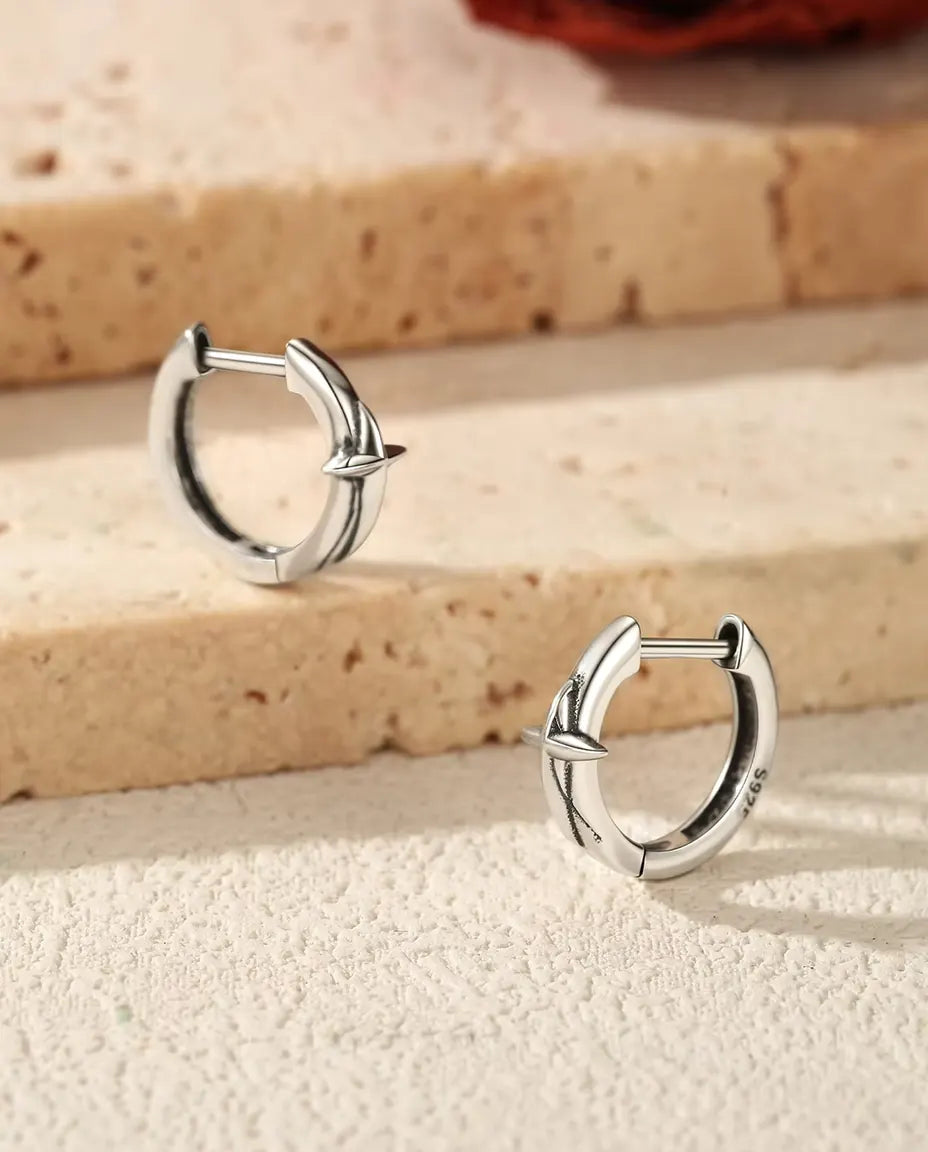 Orecchini a Cerchio Huggie con Stella in Argento 925 - la coppia su gradini di travertino