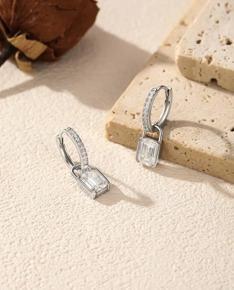 Orecchini a Cerchio Lucchetto Moissanite in Argento 925 - disposti accanto a una lastra di travertino