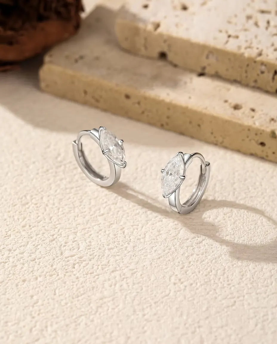 Orecchini a Cerchio Moissanite in Argento 925 - la coppia affiancata su una superficie chiara ruvida