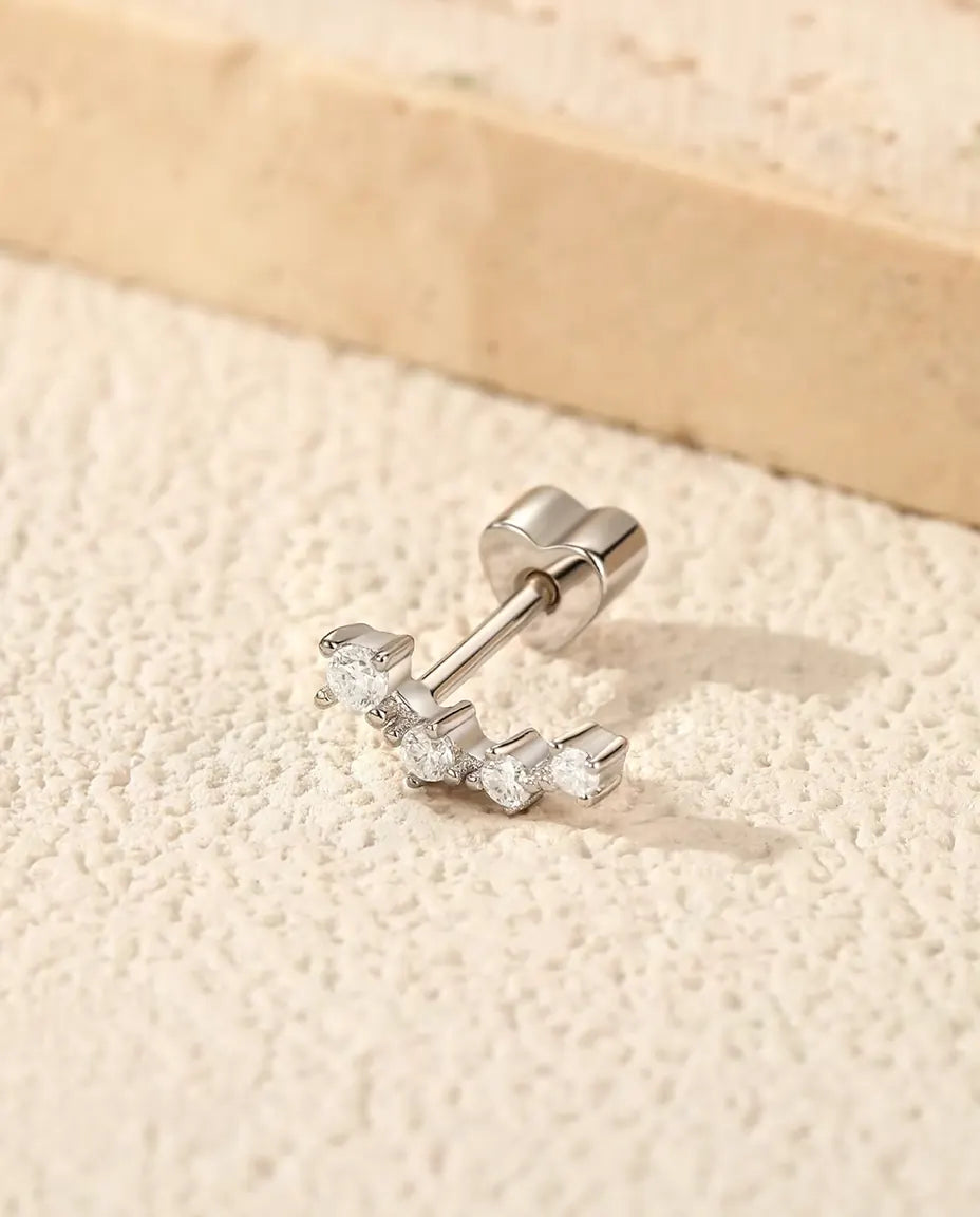 Orecchini Climber con Moissanite in Argento 925 - su una superficie chiara ruvida accanto a una lastra di travertino