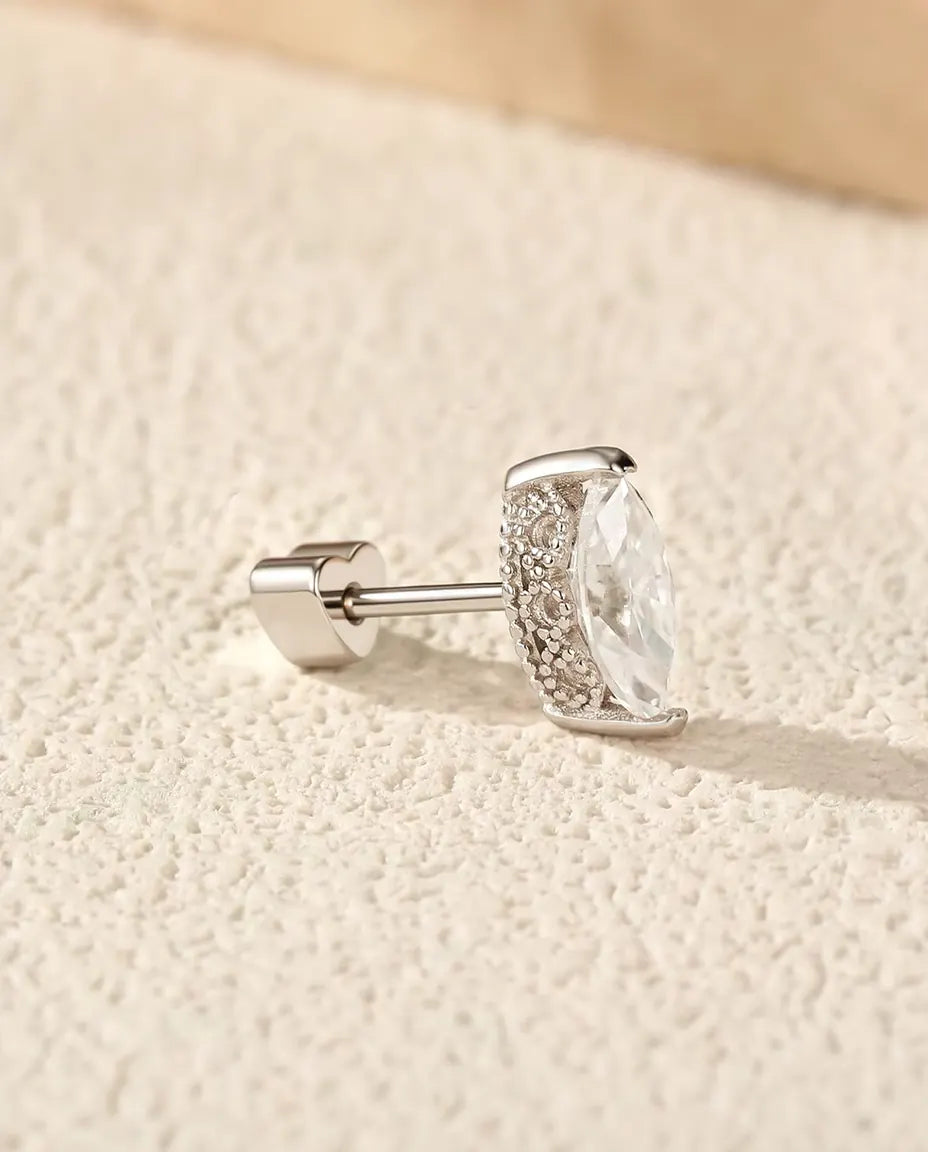Orecchini con Moissanite Marquise 4 x 8 mm in Argento 925 - su una superficie chiara ruvida accanto a una lastra di travertino