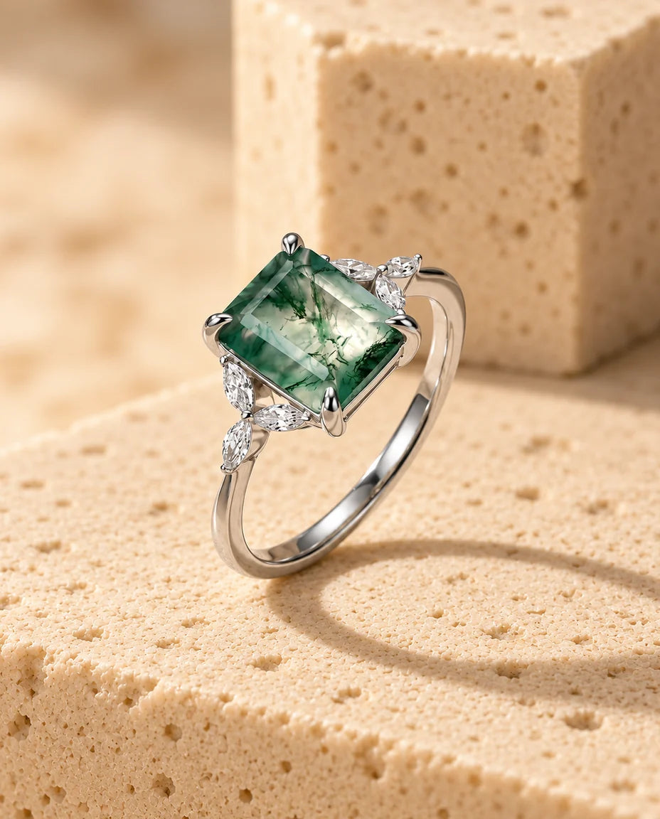 Anello in Agata Muschiata Taglio Smeraldo 7x9 mm - esposto su un blocco di travertino