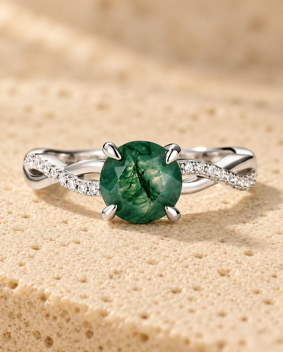 Anello Agata Muschiata Tonda Sfaccettata - appoggiato in piano su una superficie chiara ruvida