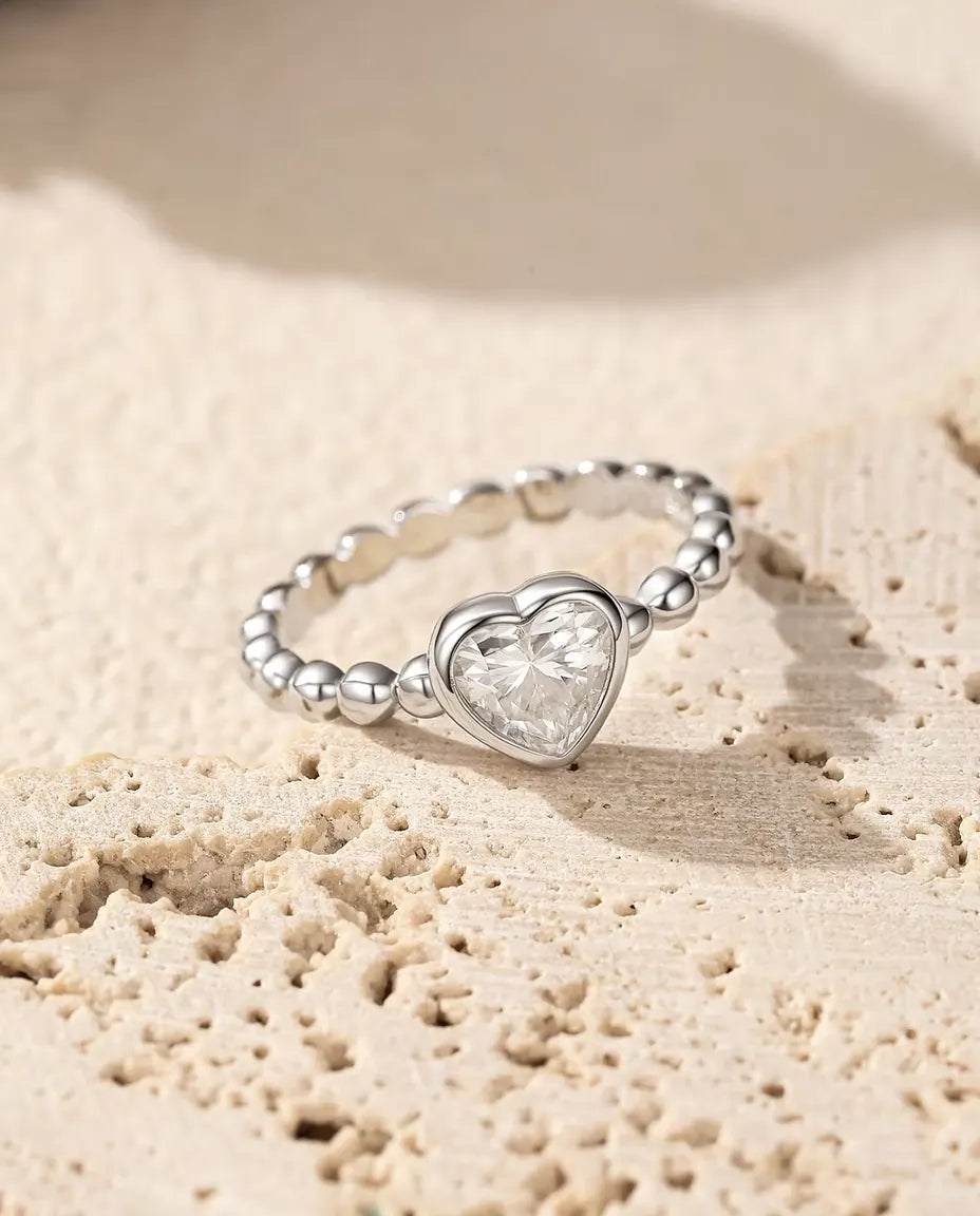 Anello Cuore Moissanite in Argento 925 - appoggiato su una superficie di travertino poroso