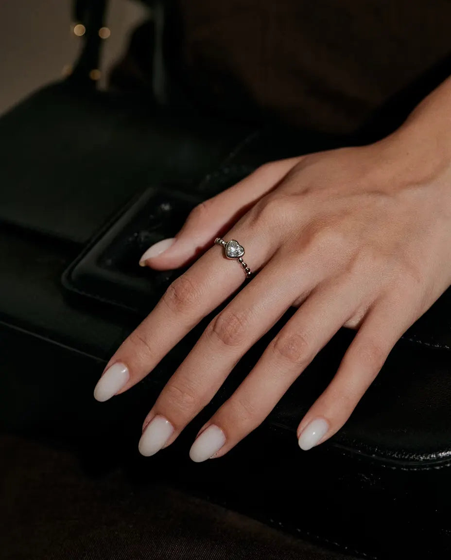 Anello Cuore Moissanite in Argento 925 - indossato su una mano appoggiata su una borsa nera