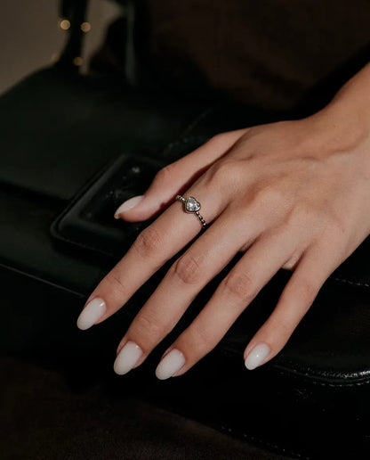 Anello Cuore Moissanite in Argento 925 - indossato su una mano appoggiata su una borsa nera