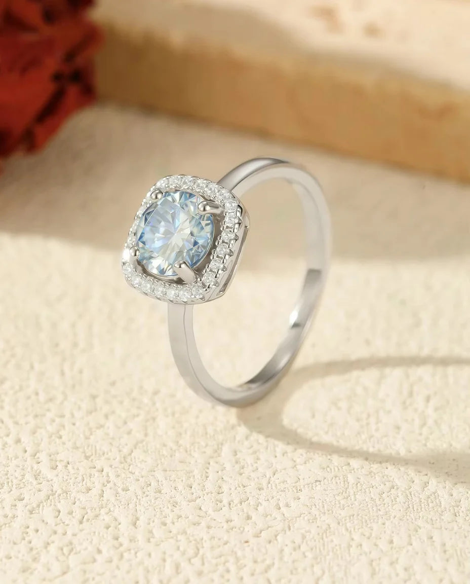 Anello Moissanite Blu Mare da 1 Carato VVS1 in Argento 925 - esposto su un blocco di travertino