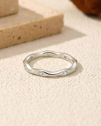 Anello Moissanite Onda in Argento 925 - appoggiato in piano su una superficie chiara ruvida