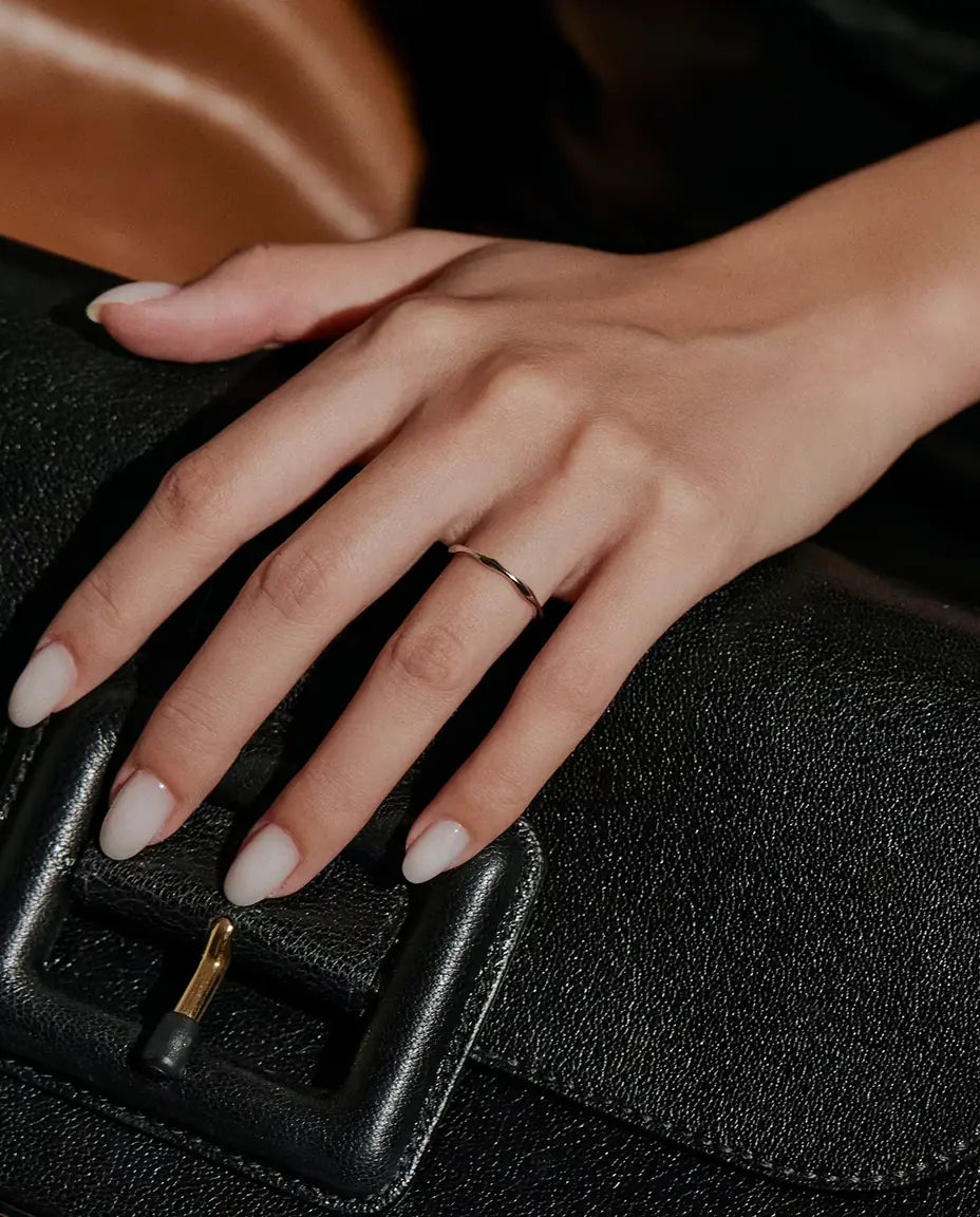 Anello Onda in Argento 925 - indossato su una mano appoggiata su una borsa nera