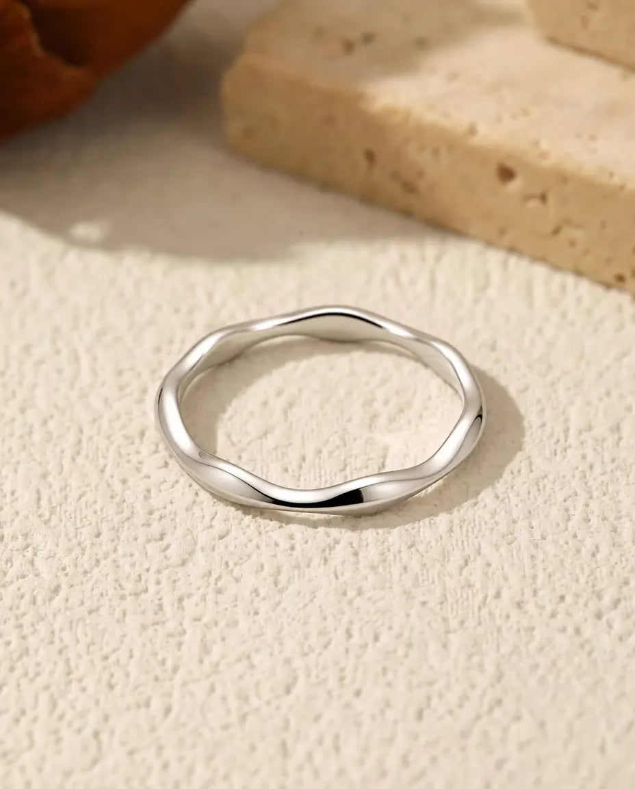 Anello Onda in Argento 925 - appoggiato in piano su una superficie chiara ruvida