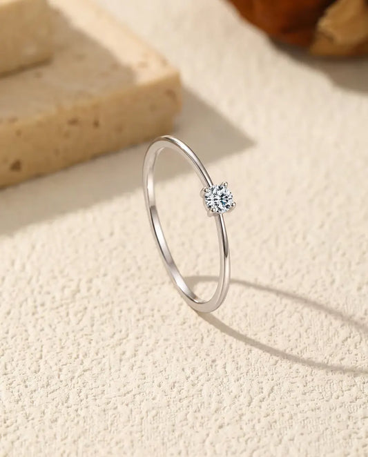 Anello Solitario Moissanite Sottile in Argento 925 - in piedi su una superficie chiara ruvida