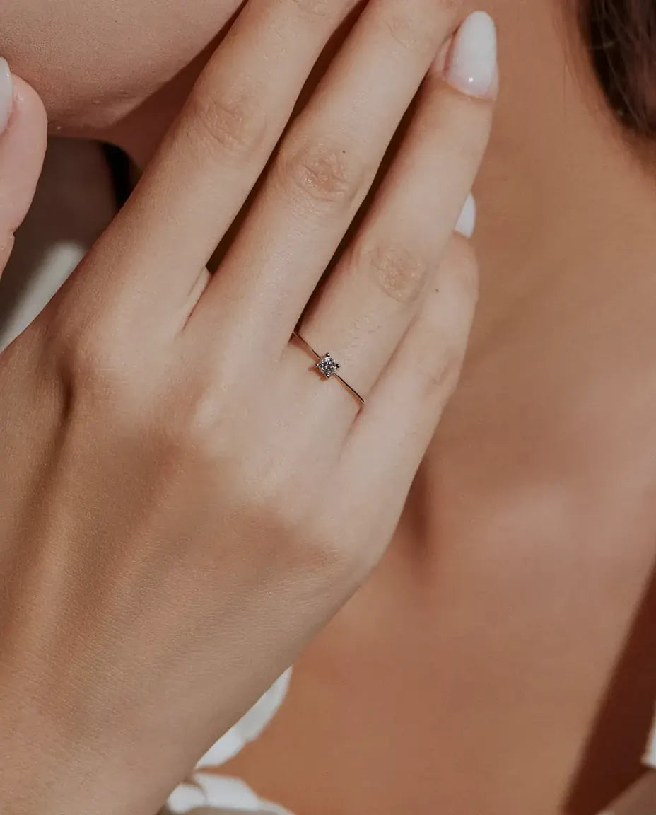 Anello Solitario Moissanite Sottile in Argento 925 - indossato da una modella con le mani vicino al viso