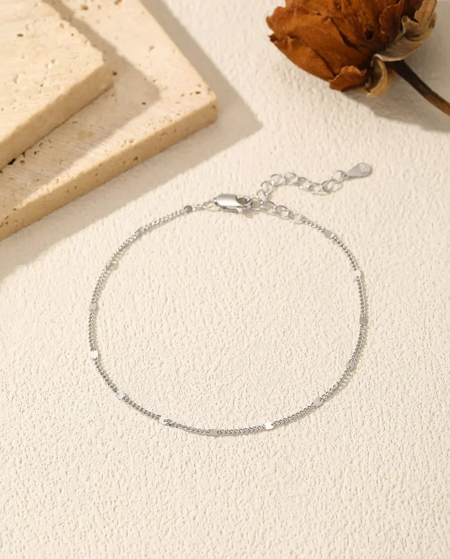 Bracciale Catena con Paillettes in Argento 925 - disteso su una superficie chiara ruvida, con chiusura e prolunga