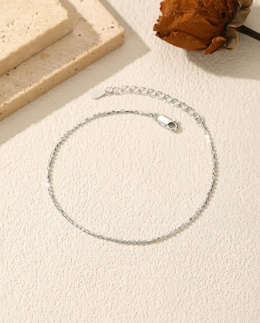 Bracciale Catena Diamantata in Argento 925 - disteso su una superficie chiara ruvida, con chiusura e prolunga