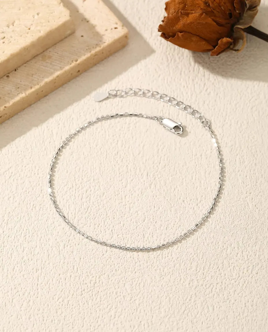 Bracciale Catena Diamantata in Argento 925 - disteso su una superficie chiara ruvida, con chiusura e prolunga