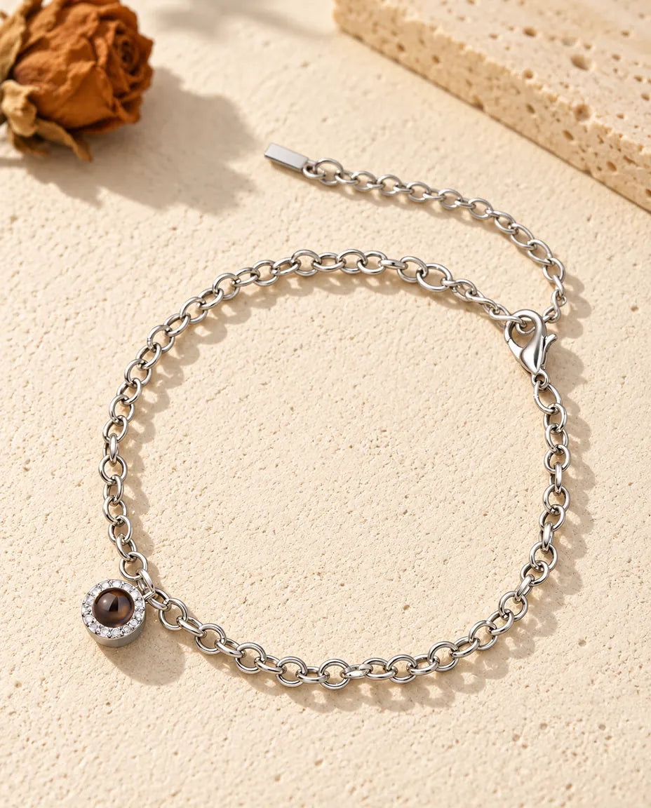 Bracciale con foto dentro argentato, mini charm tondo con zirconi su catenina sottile, posato sul gesso