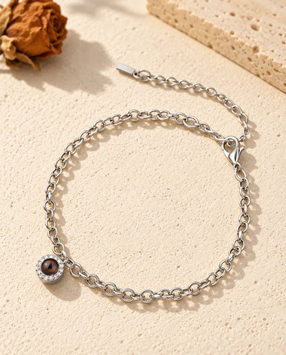Bracciale con foto dentro argentato, mini charm tondo con zirconi su catenina sottile, posato sul gesso