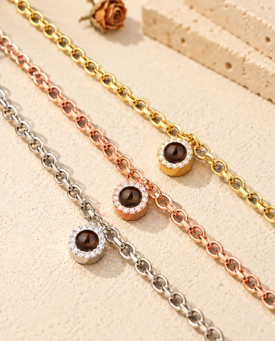 Primo piano di tre bracciali con charm tondo a pavé: dorato, color oro rosa e argentato
