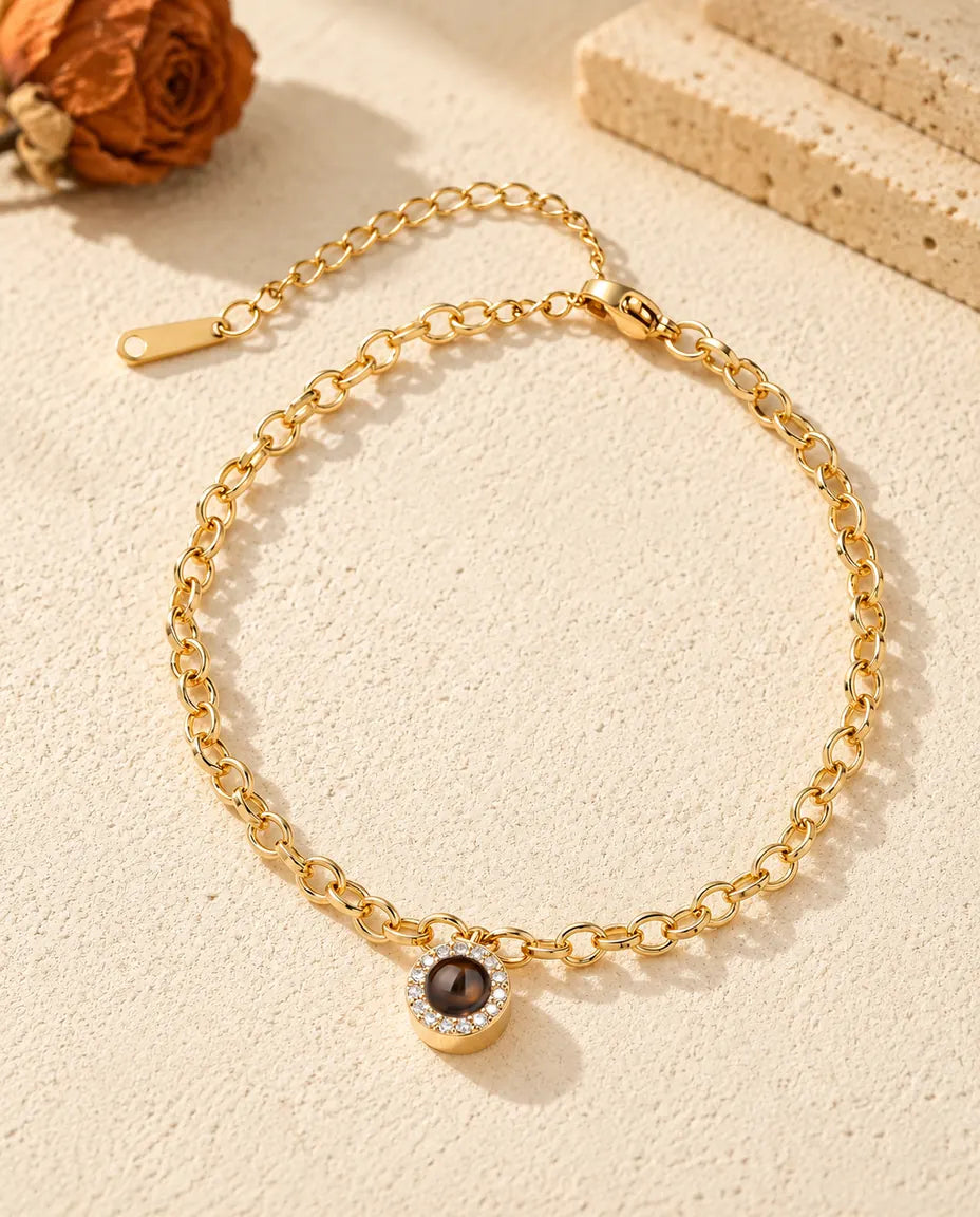 Vista dall'alto del bracciale dorato con charm tondo a pavé e la sua catenina di prolunga
