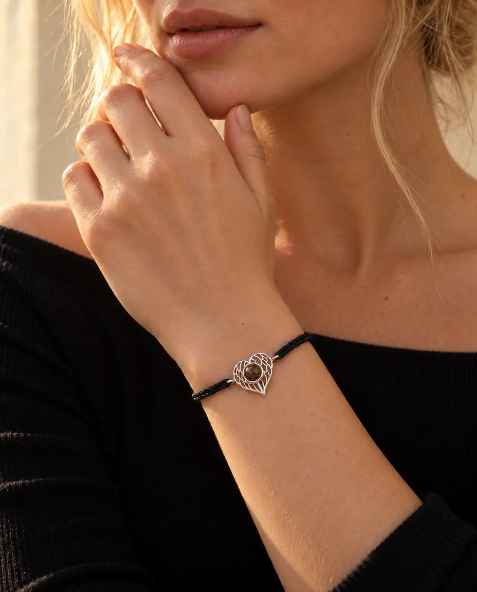 Donna con le dita sulla mascella che indossa il bracciale argentato con cuore ad ali d'angelo su cordino