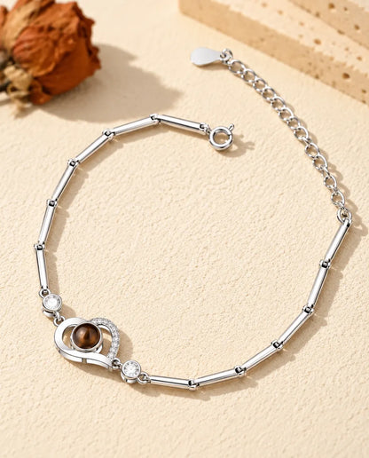 Bracciale con foto dentro argentato con cuore aperto su catena sottile a barrette, sul gesso crema