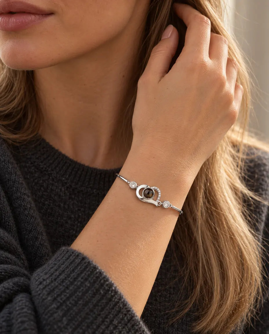 Donna con la mano tra i capelli che indossa il bracciale argentato con cuore aperto e foto dentro
