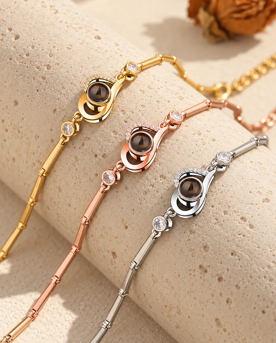 Tre bracciali con cuore aperto, dorato, color oro rosa e argentato, su un blocco di travertino