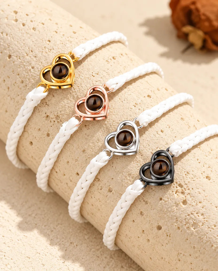 Bracciali su cordino intrecciato bianco con cuore aperto allineati, uno per ogni colore del charm