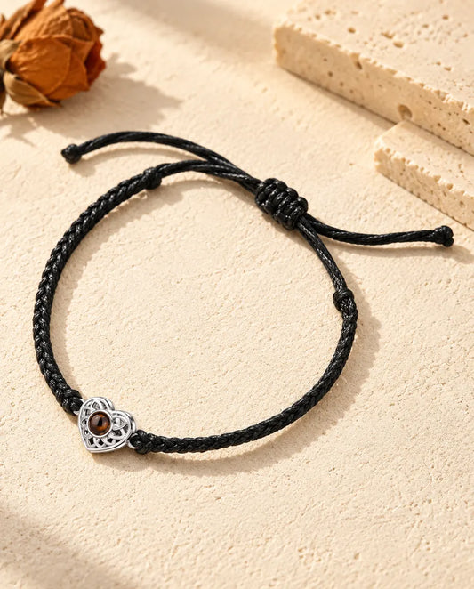 Bracciale con foto dentro: cuore traforato argentato su cordino intrecciato sottile nero, sul gesso crema