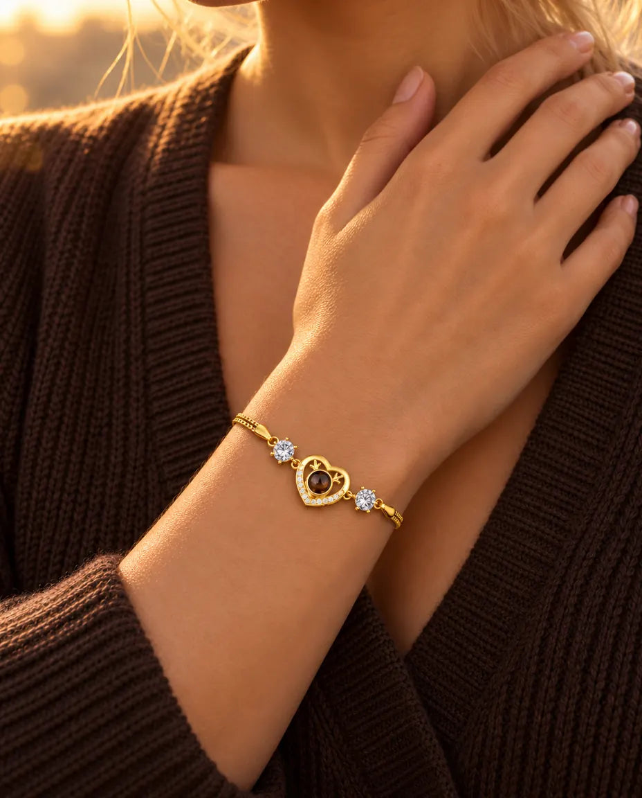 Primo piano del bracciale dorato con cuore e zirconi al polso, con la mano appoggiata vicino alla clavicola
