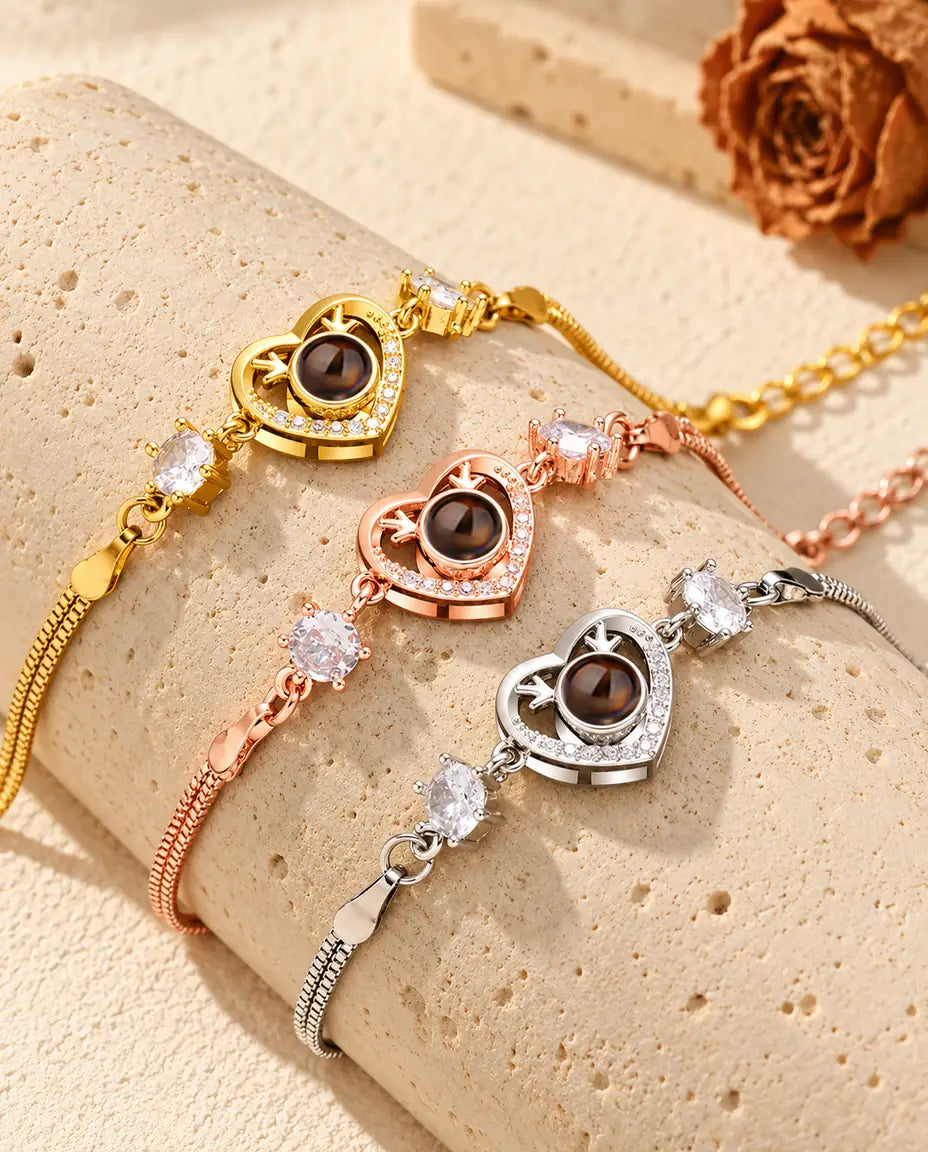 Tre bracciali con cuore e corna di cervo, dorato, color oro rosa e argentato, adagiati su un blocco di travertino
