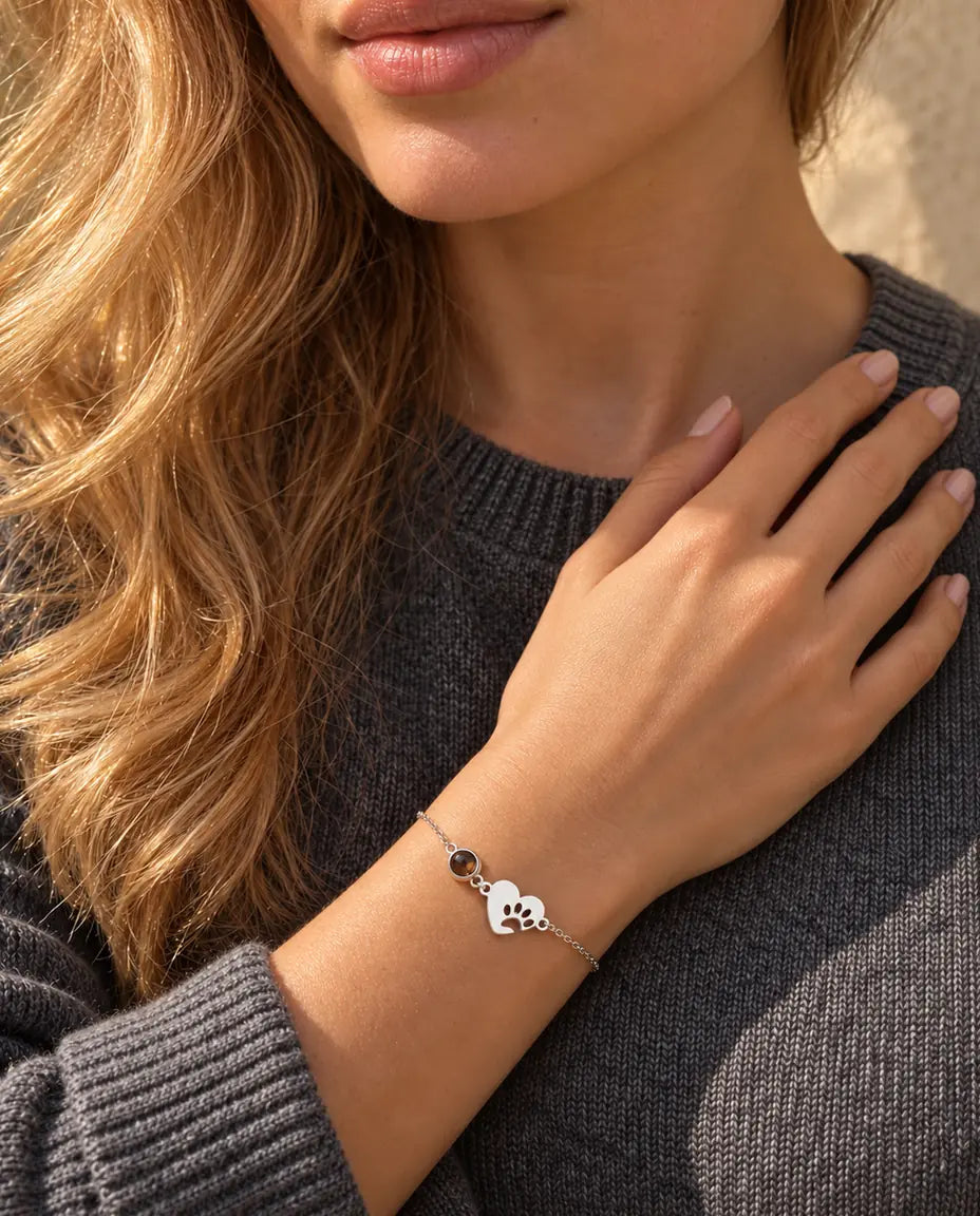 Donna con le dita sulla clavicola che indossa il bracciale argentato con cuore e impronta di zampa